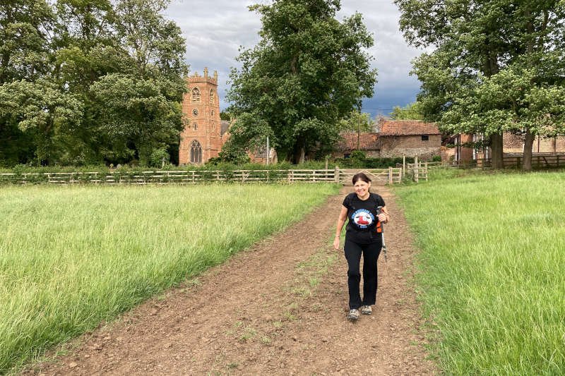 Hiker walking away from a church, across a field