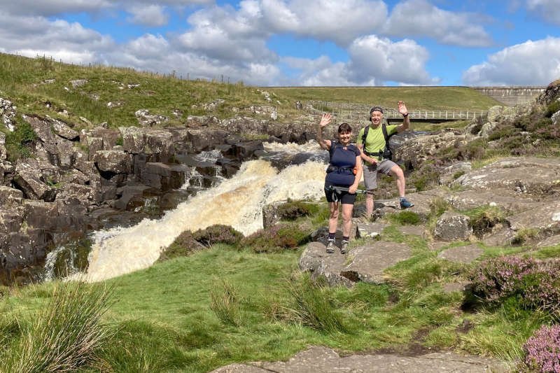 waving hikers in front of a waterfall